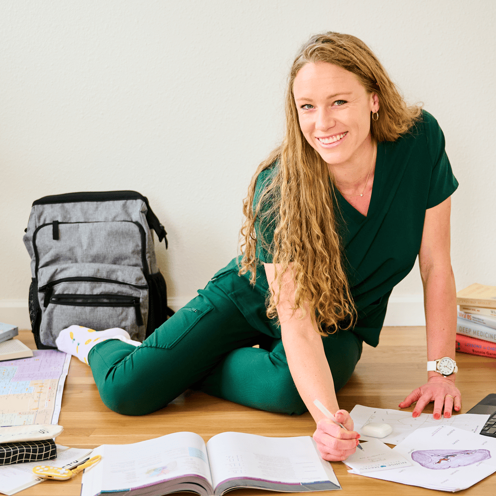 A woman sitting on the floor wearing green scrubs.