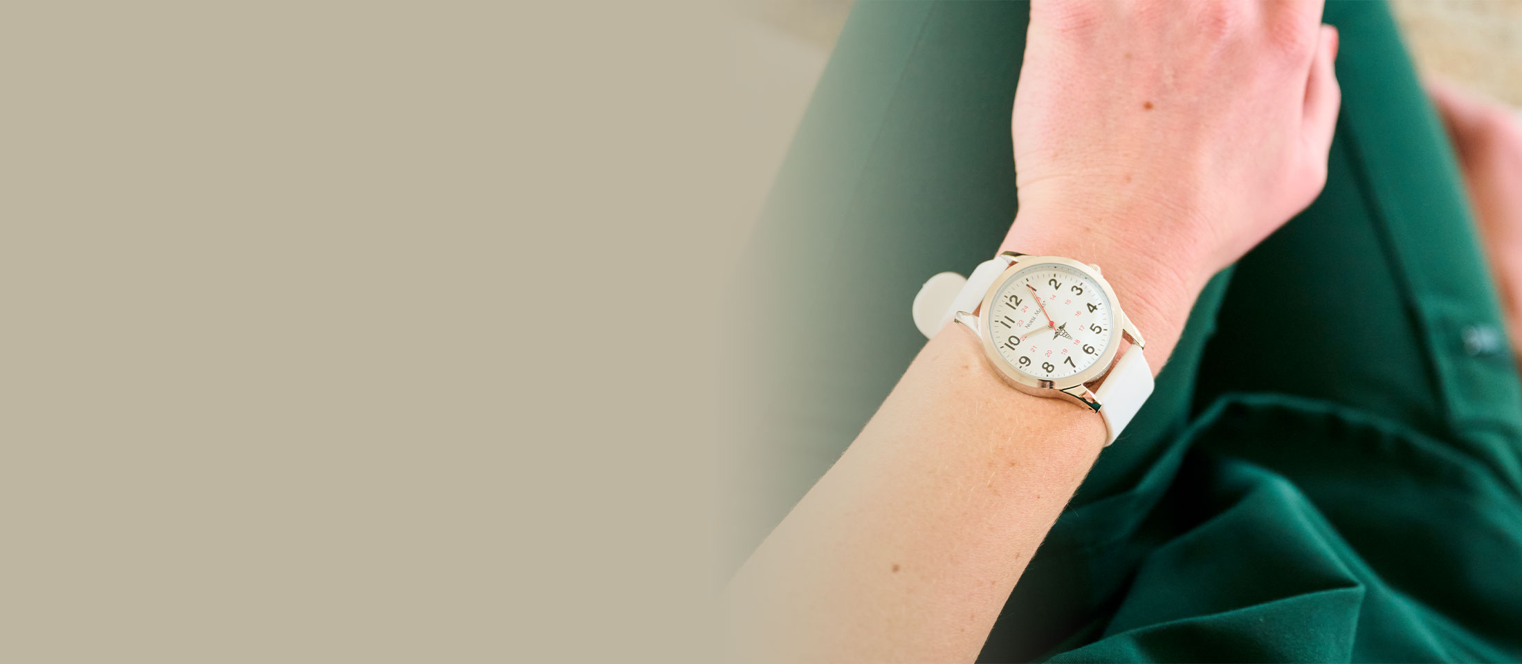 White Sweep Watch worn on wrist, sitting in a lap, with green scrubs on.