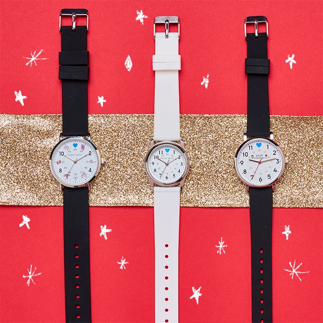 Three watches in white and black on a gold ribbon beneath their dial. Shop Watches.