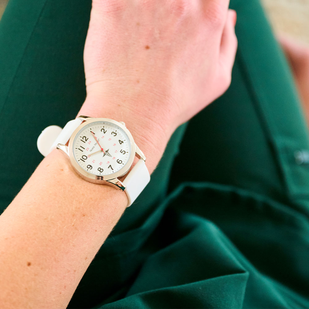 White Sweep Watch worn on wrist, sitting in a lap, with green scrubs on.