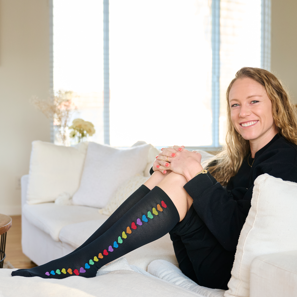 A woman sitting in a chair wearing black compression socks with hearts.