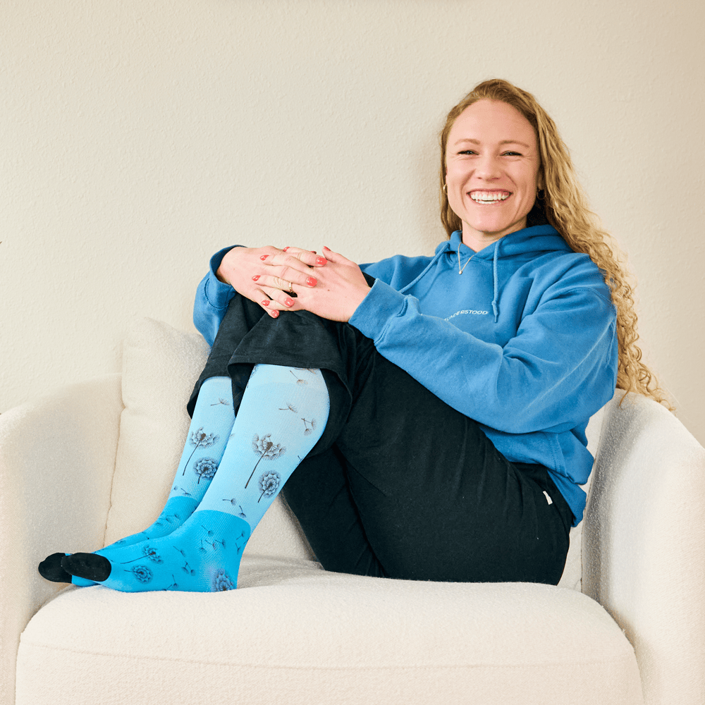 A woman sitting in a chair wearing blue compression socks.