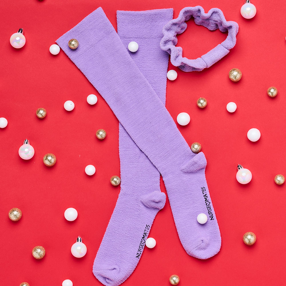 Women’s Luxe Compression and Headband set in purple shown flat on a red background surrounded by baubles.